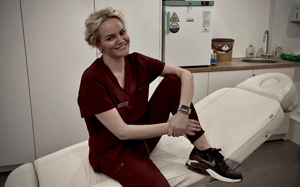 Professional beauty therapist seated in a modern treatment room at the salon.